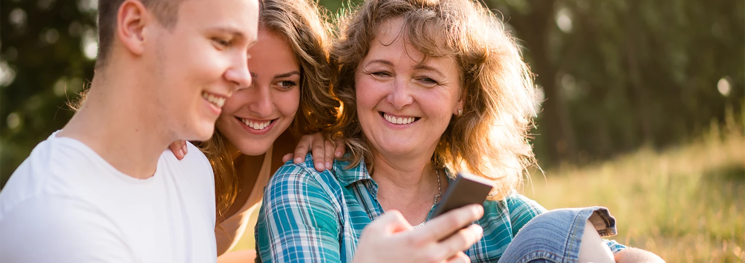 Woman and teenage son and daughter looking at phone
